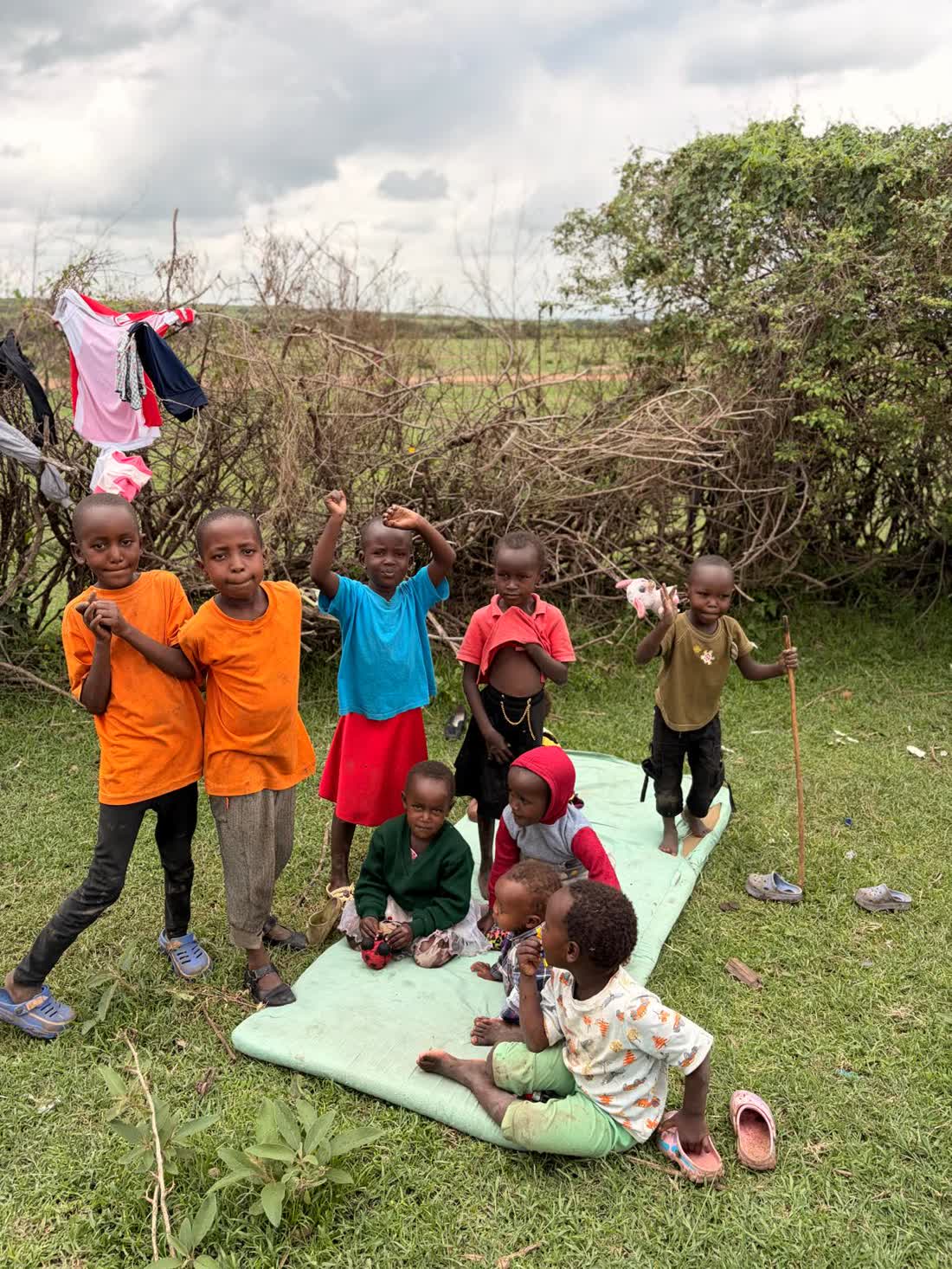 A group of Maasai children gathered on the earthen ground beside their homes