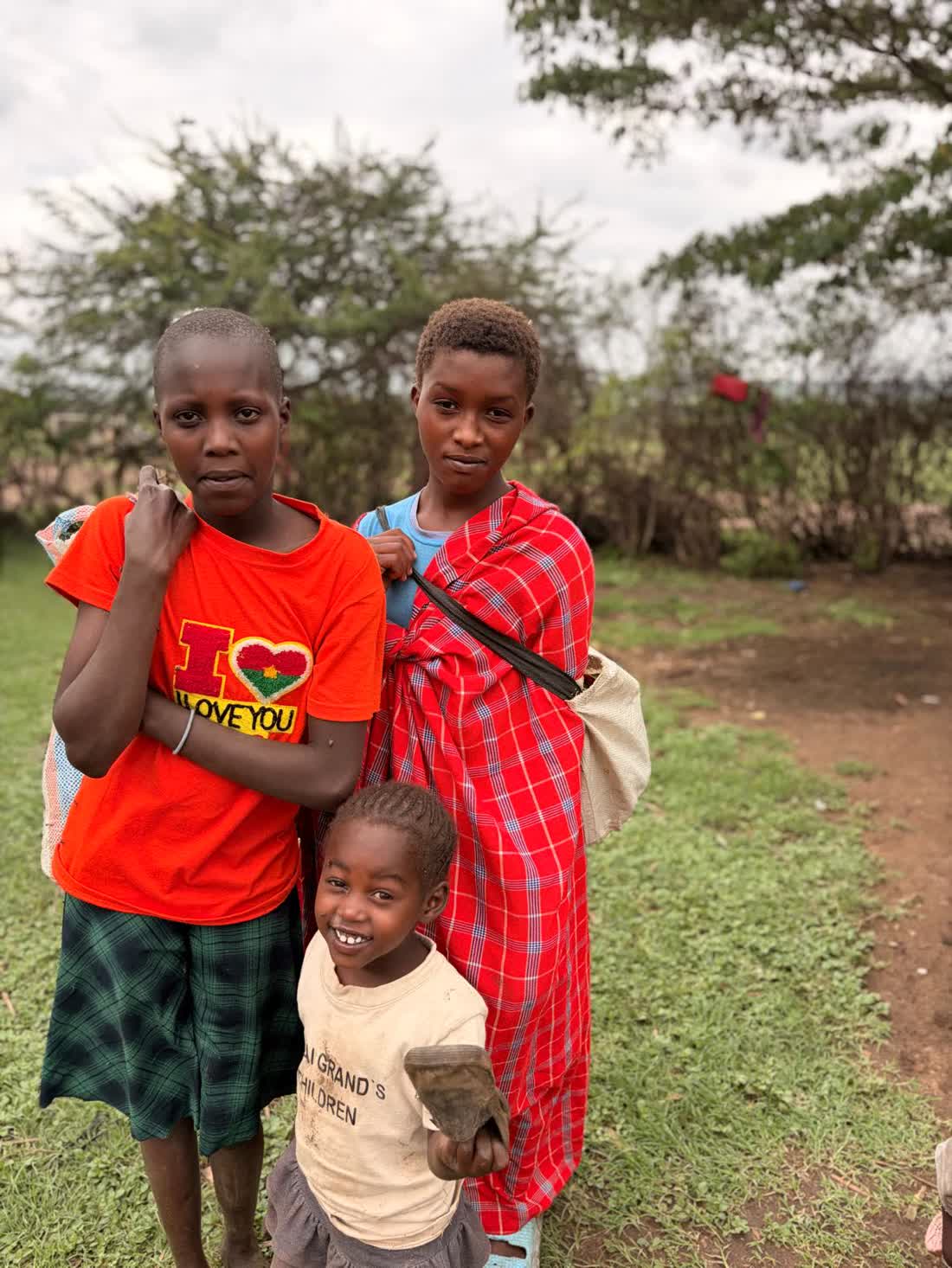 Three Maasai children standing together outdoors for a portrait