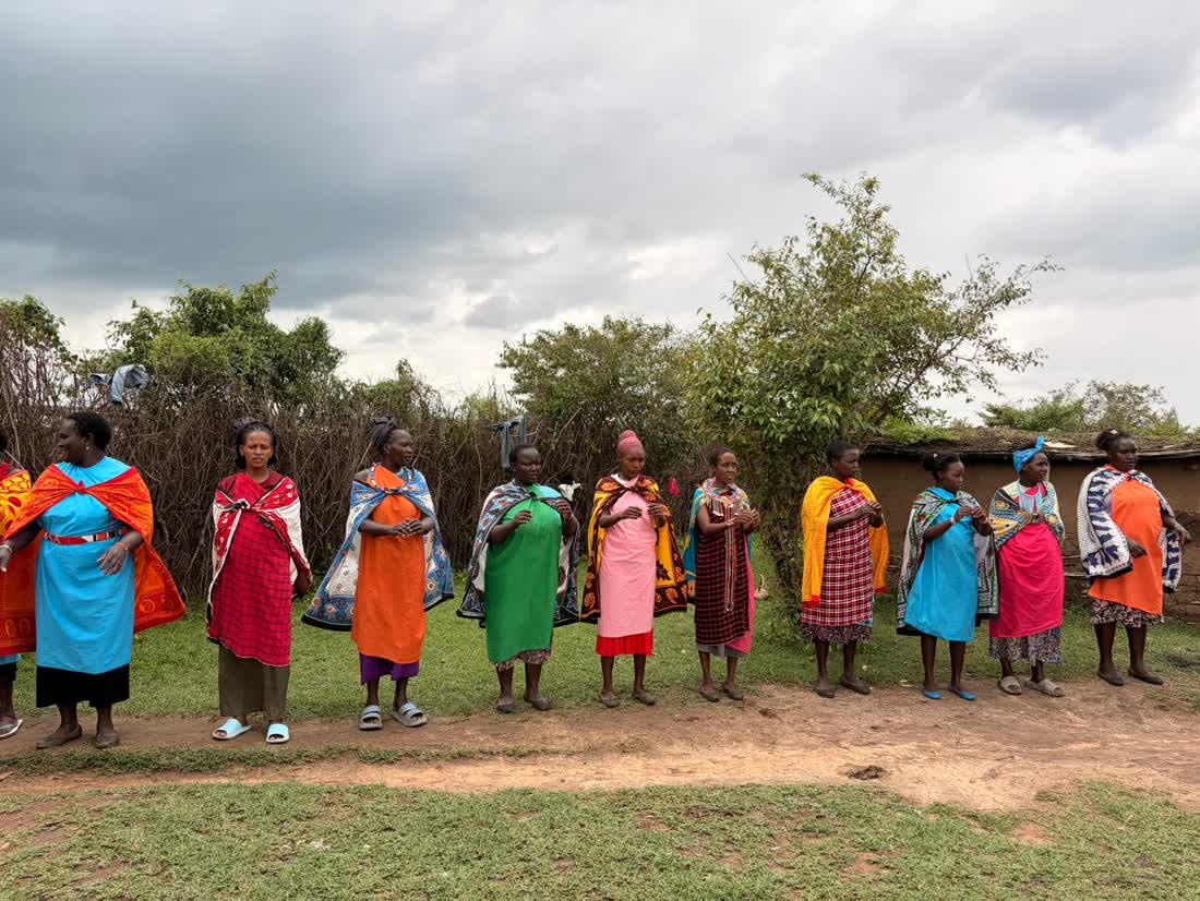 Maasai women in colourful dress singing together in a village