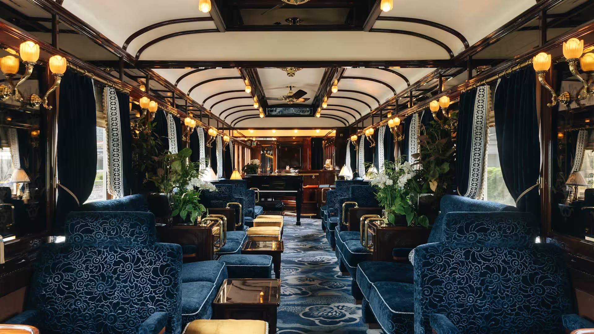 Blue velvet lounge car with brass lamps and a grand piano