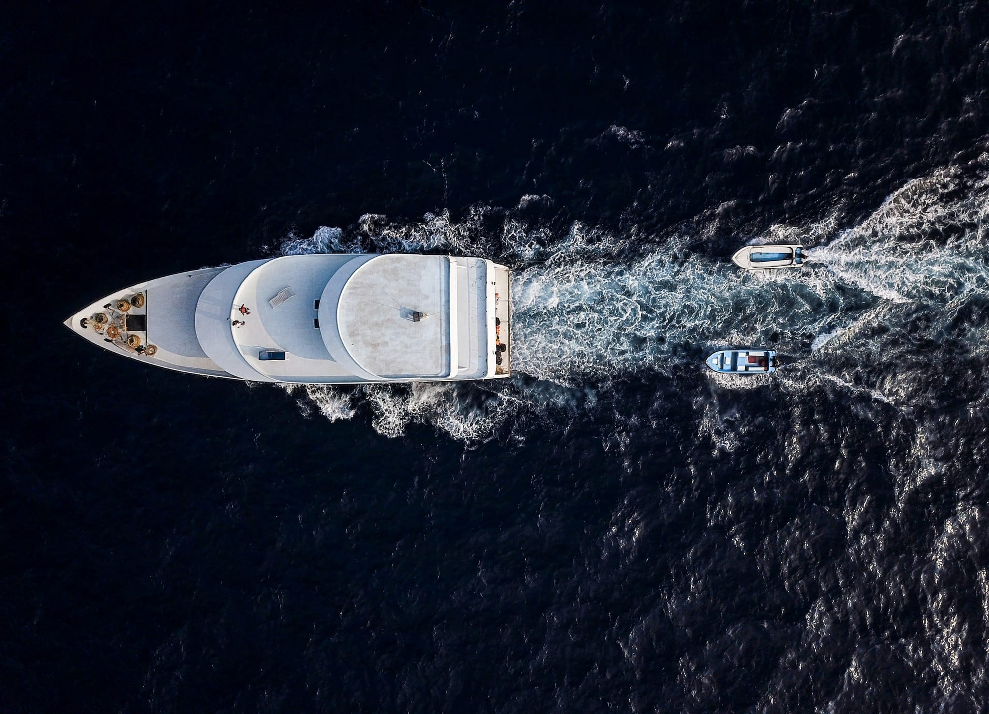A luxury yacht and tenders crossing the deep blue ocean from above